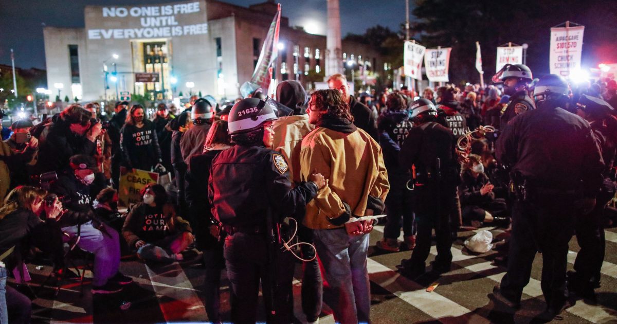 Police officers detain pro-Palestinian protesters who are blocking the street near the home of Senate Majority Leader Chuck Schumer in New York City on Tuesday.