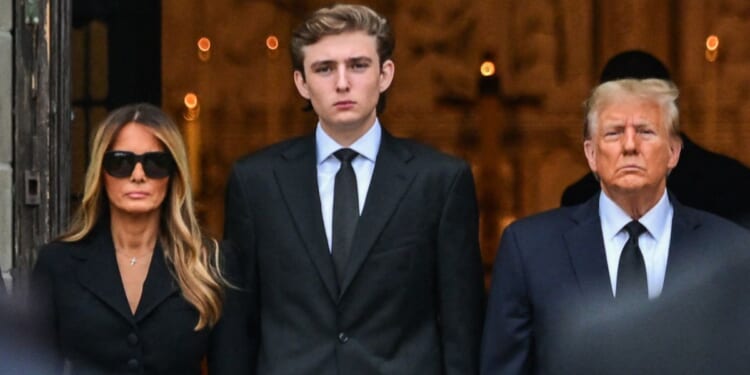 Former President Donald Trump, right, stands with his wife, Melania Trump, and their son, Barron Trump, as the coffin carrying the remains of Amalija Knavs, the former first lady's mother, is carried into the Church of Bethesda-by-the-Sea for her funeral in Palm Beach, Florida, on Jan. 18.