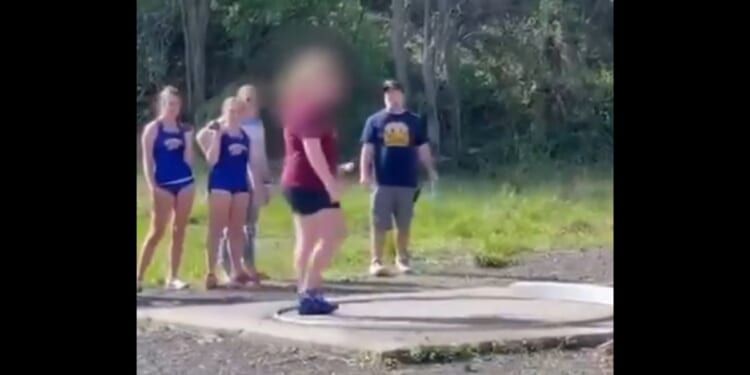 Girls watch while a boy claiming to be a girl gets ready to shot put at a track meet in West Virginia.