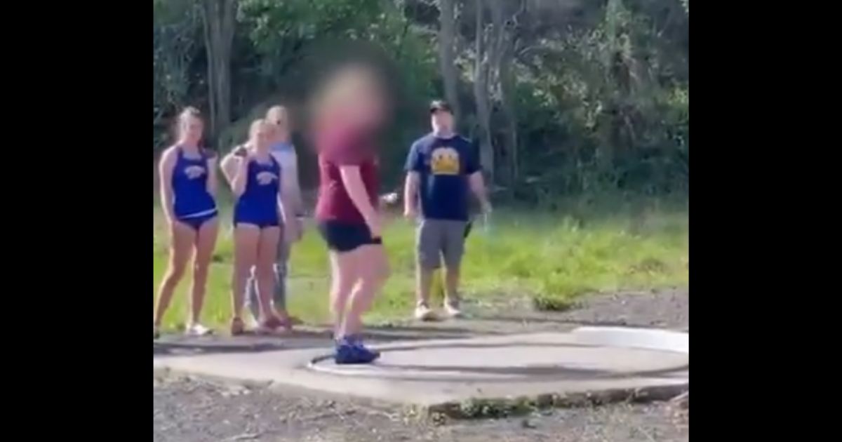 Girls watch while a boy claiming to be a girl gets ready to shot put at a track meet in West Virginia.