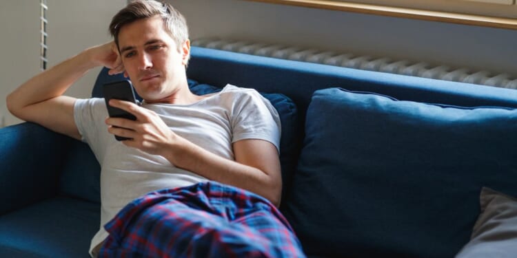 A man looks at a cellphone in this stock image.