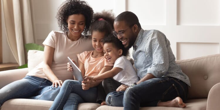 A stock photo shows a happy family sitting on the couch together.