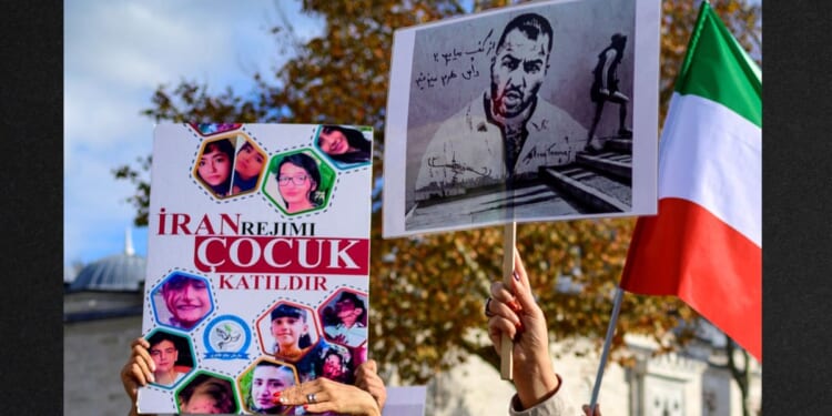 People hold placards bearing portraits of imprisoned Iranian rapper Toomaj Salehi , right, and portraits of children, left , who were killed during protests in Iran in a file photo from November 2022. Salehi has reportedly been sentenced to death for his criticism of the Iranian regime.