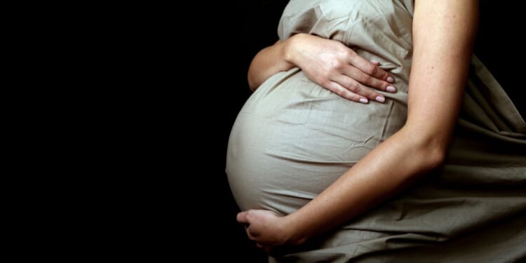 This photo shows a pregnant mother holding her stomach.