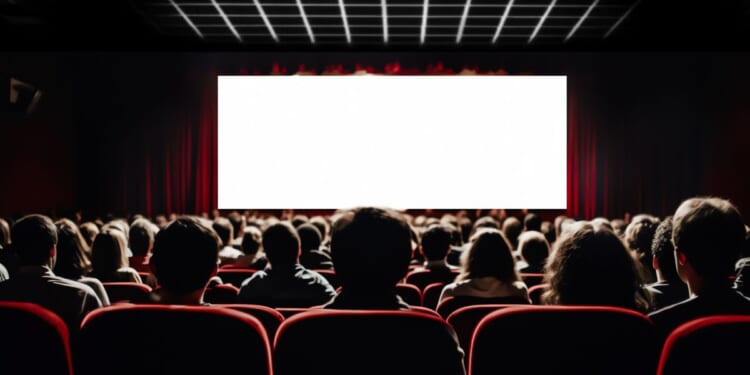 The audience of a full movie theater looking at a white screen.