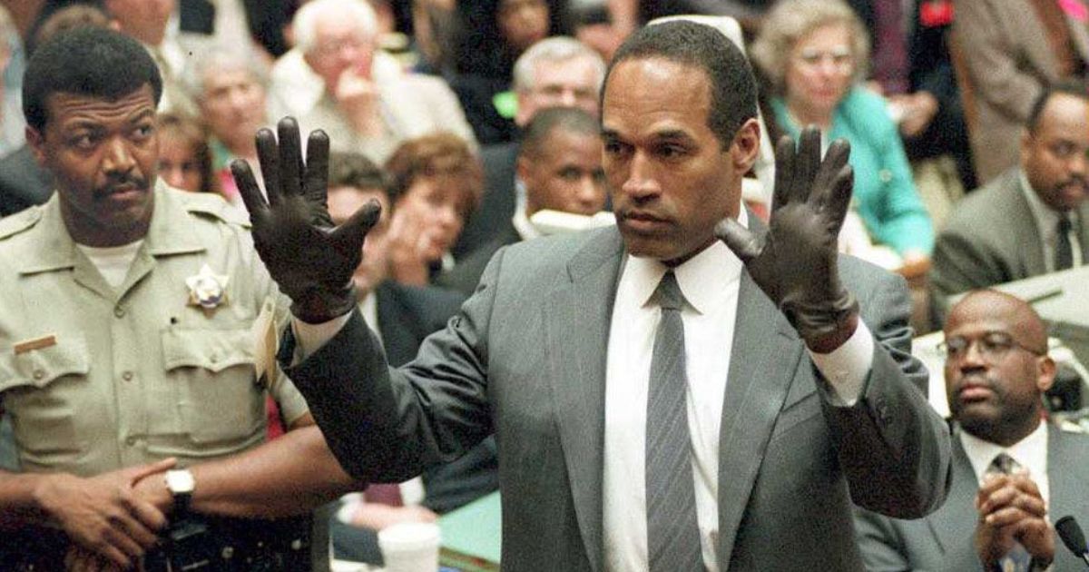 O.J. Simpson shows the jury a new pair of Aris extra-large gloves, similar to the gloves found at the Bundy and Rockingham crime scene 21 June 1995, during his double murder trial in Los Angeles,CA. Deputy Sheriff Roland Jex(L) and Prosecutor Christopher Darden (R) look on.