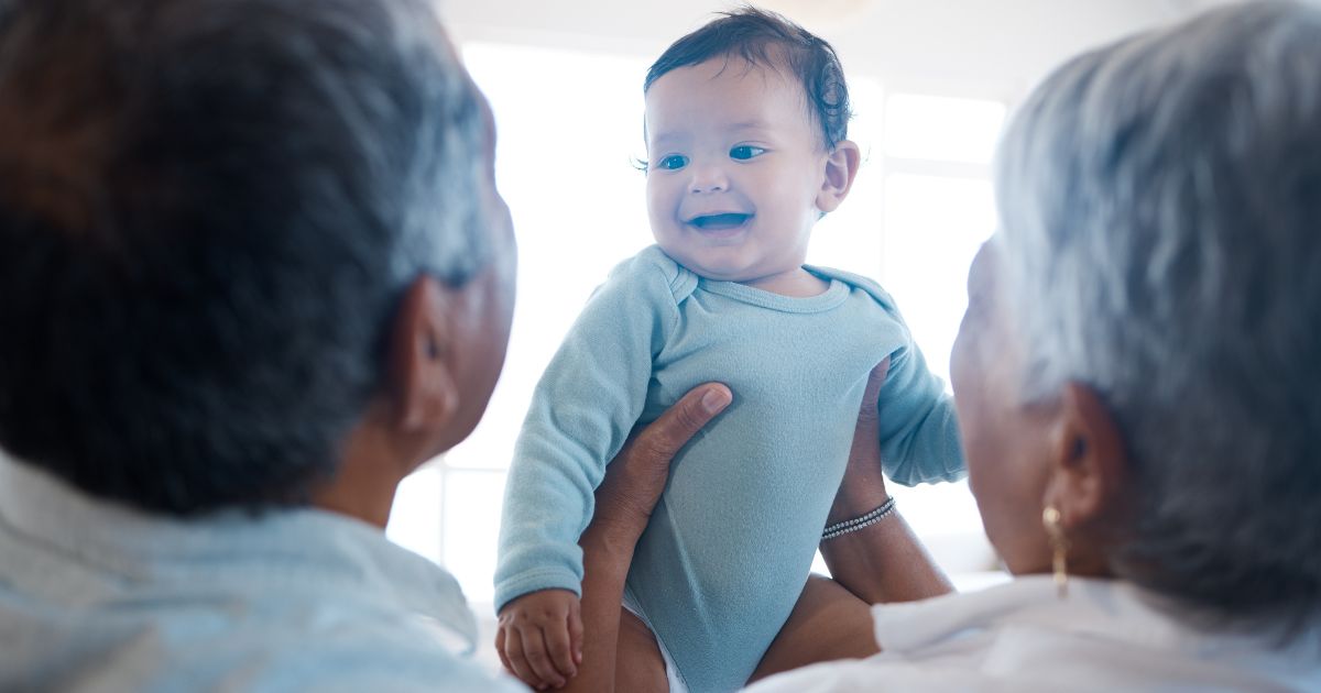 A stock photo shows a couple holding their grandchild.