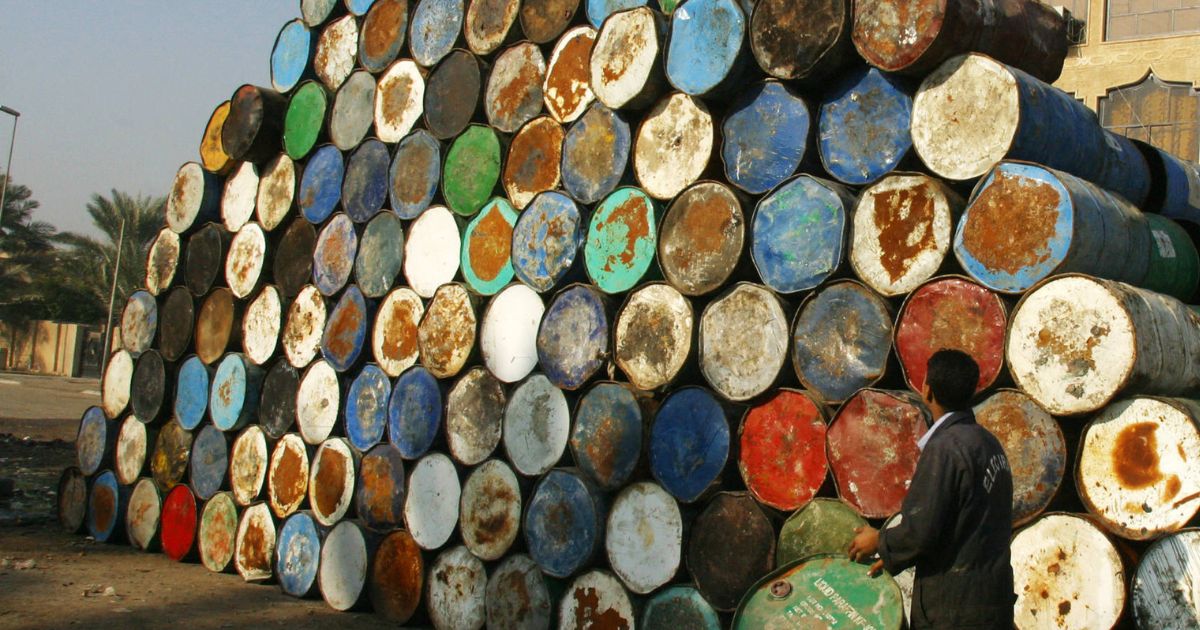 A worker surveys a stack of empty oil drums as he brings another to add to it at a warehouse in Baghdad, Iraq, on Jan. 6.