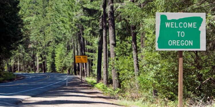 a roadside sign in the forest that says "welcome to Oregon"