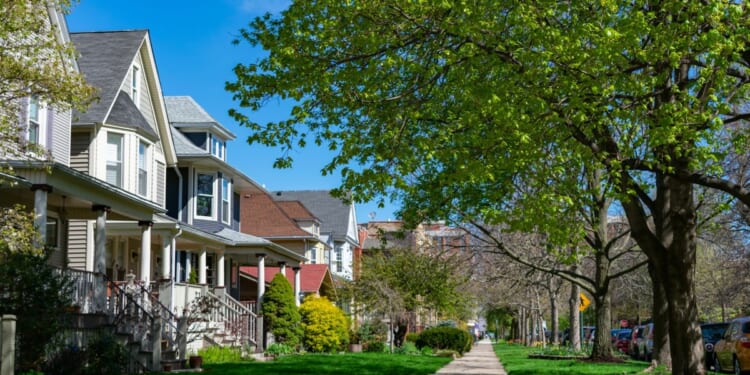 A row of old wooden homes with front lawns and a sidewalk is pictured in the North Center neighborhood of Chicago, Illinois.