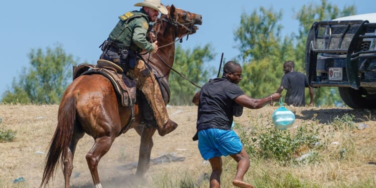 A United States Border Patrol agent on horseback uses the reins to try and stop a Haitian migrant from entering an encampment on the banks of the Rio Grande near the Acuna Del Rio International Bridge in Del Rio, Texas, on Sept. 19, 2021.