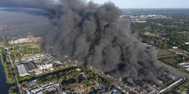 A fire burns from a vast shopping complex in Warsaw, Poland, on Sunday, May 12, 2024. The fire broke out Sunday morning in a vast shopping complex in the Polish capital that housed some 1,400 shops and service outlets and where many of the vendors were from Vietnam.