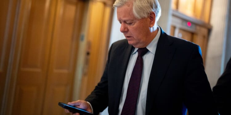 Sen. Lindsey Graham looks at his phone as he walks toward the Senate Chamber on Capitol Hill in Washington on April 23.