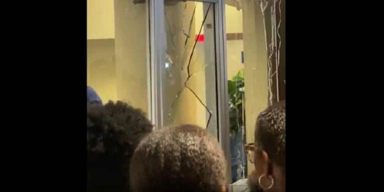 A glass door is broken as a crowd mills outside the graduation ceremony at Howard University in Washington.