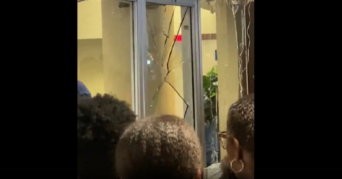 A glass door is broken as a crowd mills outside the graduation ceremony at Howard University in Washington.