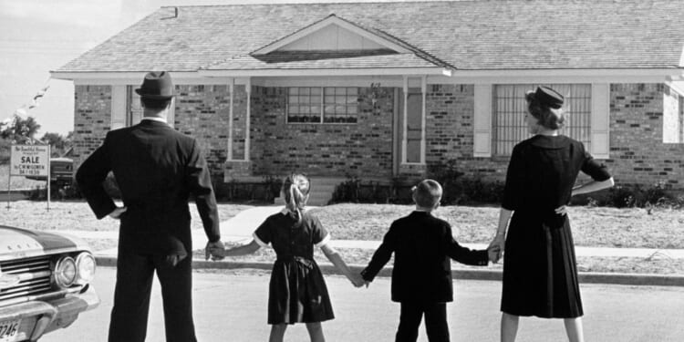 This Getty stock image shows a family in 1950 standing outside of a house for sale.