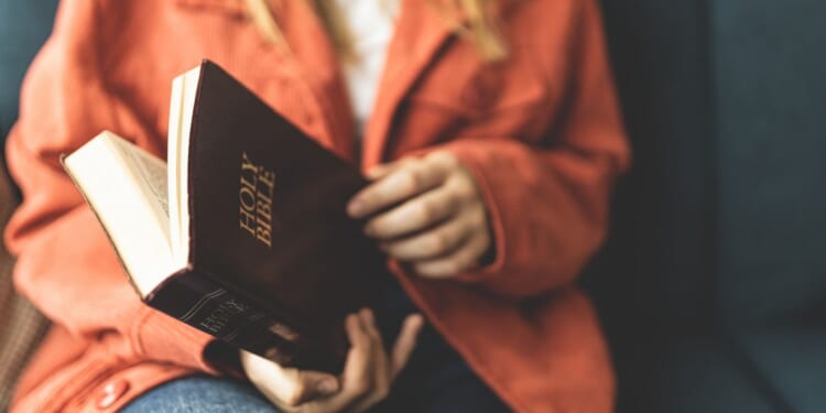 A stock photo shows a woman opening a Bible.