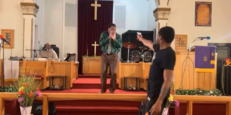 A man points a gun at Pastor Glenn Germany while he was preaching at Jesus' Dwelling Place Church in North Braddock, Pennsylvania, on Sunday.