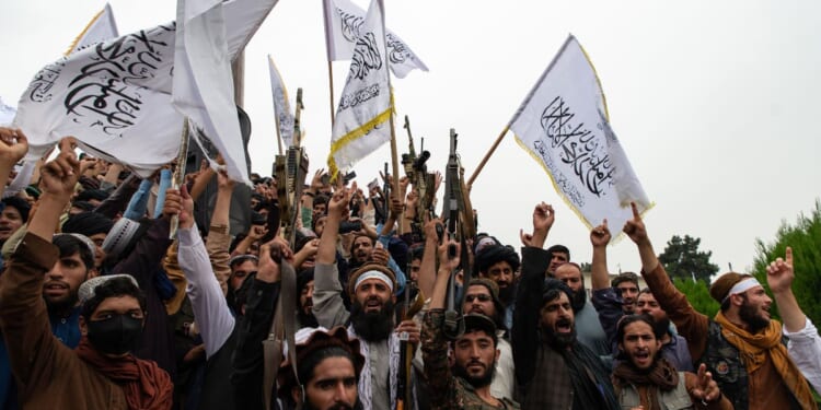 Men wave the flag of the Islamic Emirate of Afghanistan during a celebration of the first anniversary of the Taliban's return to power in Kabul, Afghanistan, on Aug. 15, 2022.