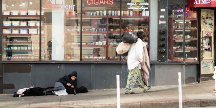 A person lies on the sidewalk in San Francisco, on November 13, 2023.