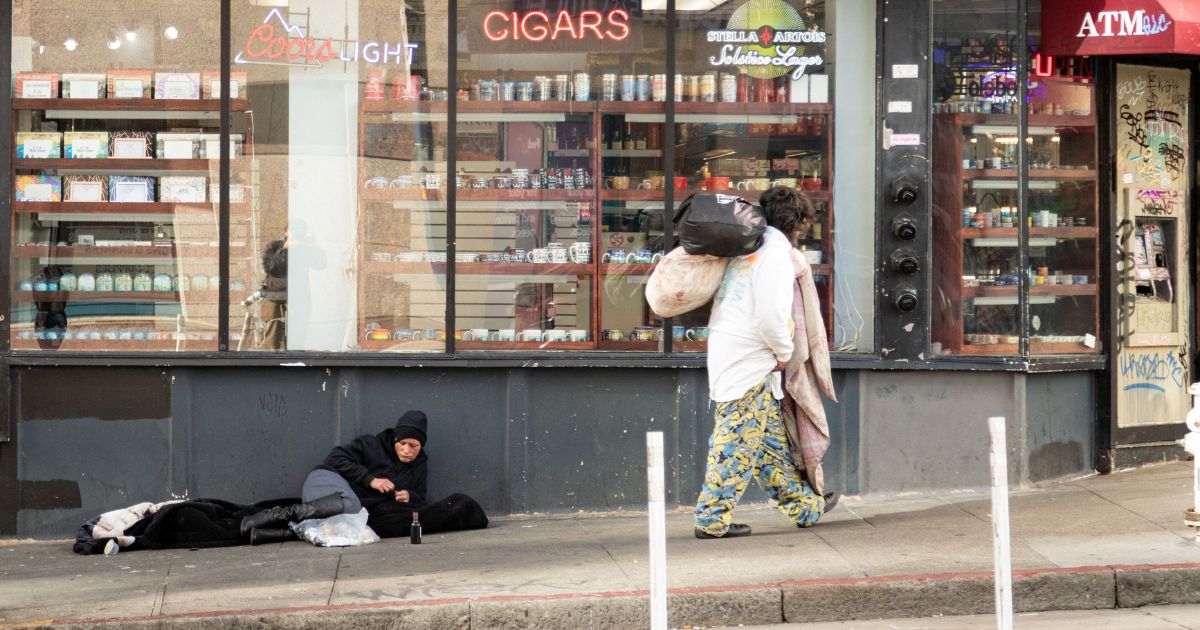 A person lies on the sidewalk in San Francisco, on November 13, 2023.