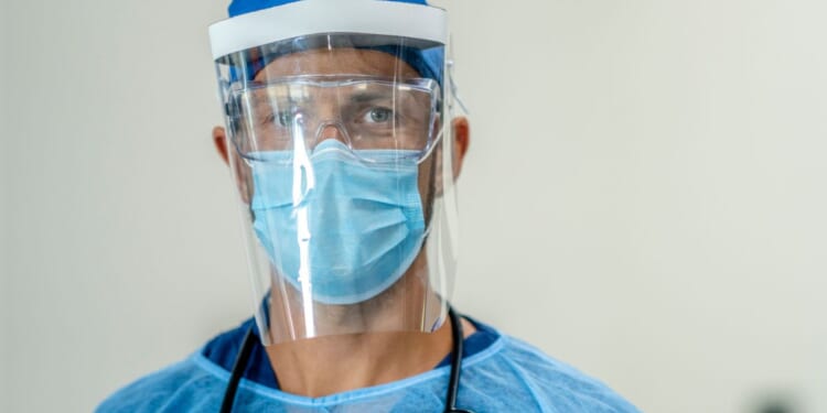 A medical professional is wearing full protective wear in a hospital setting.