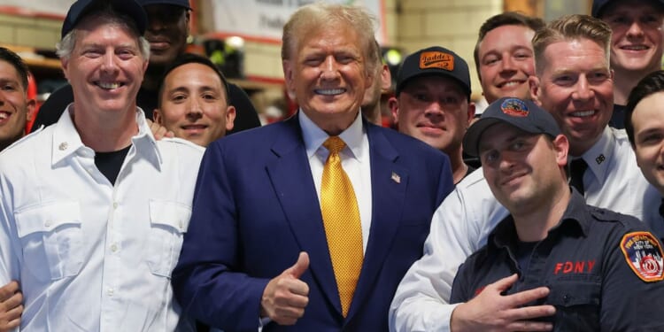 Donald Trump posing for a photo with firefighters at a midtown Manhattan firehouse