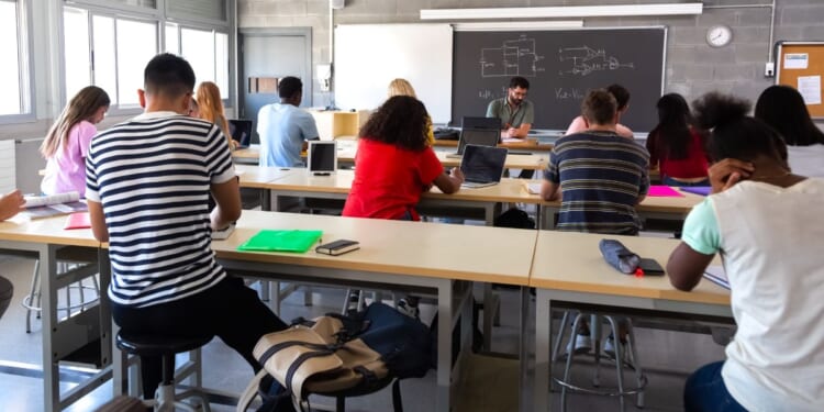 A stock photo shows high school students in a classroom.