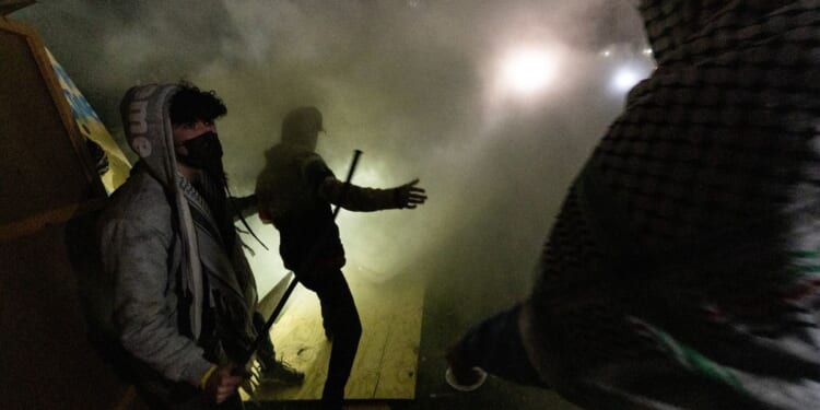 Pro-Palestinian demonstrators attempt to rebuild a barricade around their encampment while surrounded in tear gas on the campus of the University of California Los Angeles on Wednesday.