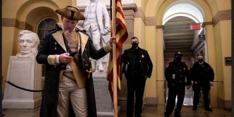 Capitol Police look on as a protester dressed as George Washington checks his phone before being pushed out of the building on Jan. 6, 2021. Supporters of then-President Donald Trump staged a mostly peaceful protest at the Capitol as Congress debated the 2020 presidential election electoral vote certification.