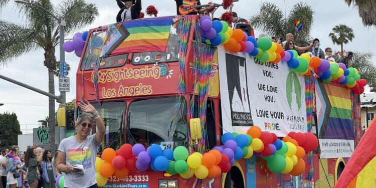 Members of the Hollywood United Methodist Church wave from a top a sightseeing bus decorated with rainbow-colored balloons and flags during the LA "Pride" Parade in Hollywood on June 11, 2023.