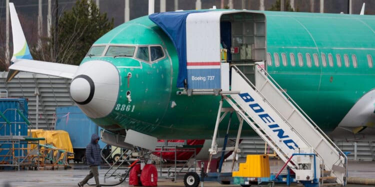 A man walks past an unpainted Boeing 737-8 MAX parked at Renton Municipal Airport adjacent to Boeing's factory in Renton, Washington, on Jan. 25.