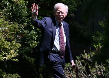 John Bolton waves as he arrives at his house, after the FBI conducted a court-authorized search at his home in Bethesda, Maryland, on Aug. 22.
