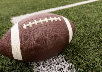 A football sits on a field in a stock photograph.