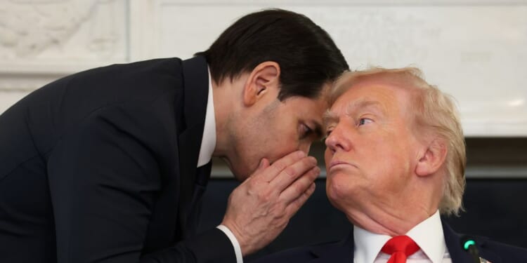 Secretary of State Marco Rubio interrupts a roundtable discussion to whisper to President Donald Trump at the White House Thursday.