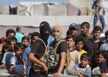 Palestinian militants of the Ezzedine al-Qassam Brigades, the military wing of Hamas, stand guard next to a crowd watching the transfer of released Israeli hostages to the Red Cross in the south of Deir el-Balah in the central Gaza Strip, on Oct. 13, 2025.