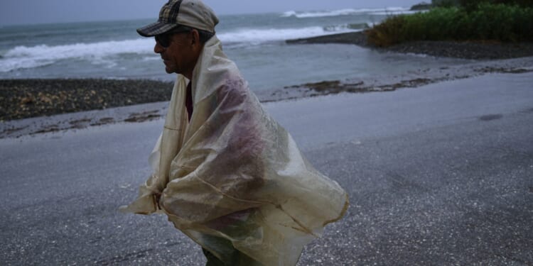 A man walks in the rain Tuesday before the arrival of Hurricane Melissa in Canizo, a community in Santiago de Cuba.