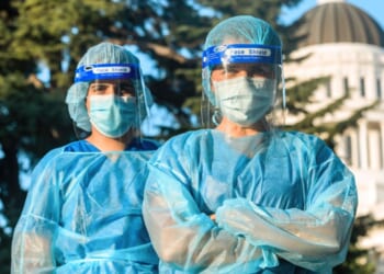 A stock photo shows masked health care workers in front of the state capitol building. Several California counties are mandating masks in health care settings from Nov.1 through March 31.