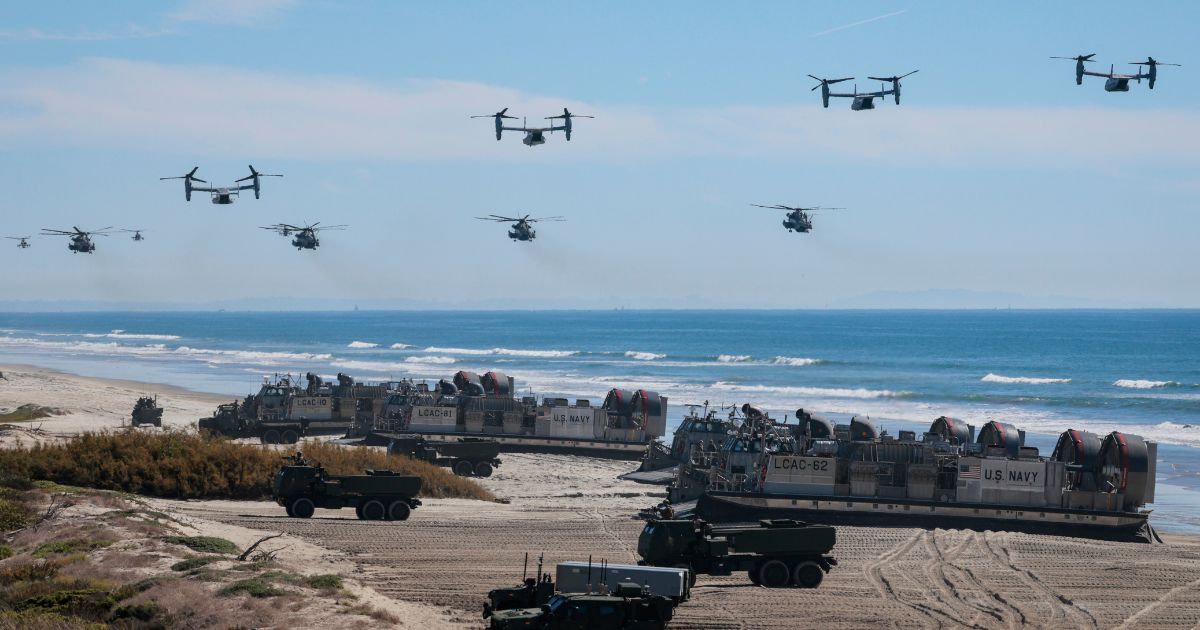 U.S. Navy Landing Craft Air Cushions unload equipment onto the beach as U.S. Marine Corps V-22 Ospreys and CH-53 Super Stallions fly overhead during the America's Marines 250 event at Camp Pendleton's Red Beach on Oct. 18, 2025, in Oceanside, California.