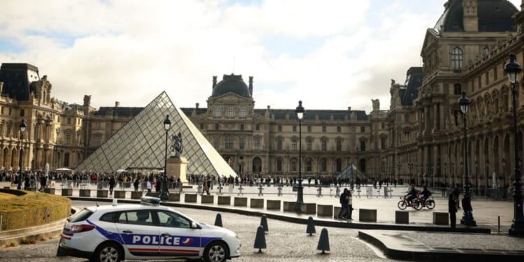 A police car parks in the courtyard of the Louvre museum in Paris, one week after the robbery on Sunday.