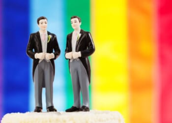 A so-called "gay" marriage wedding cake in front of a pride flag.