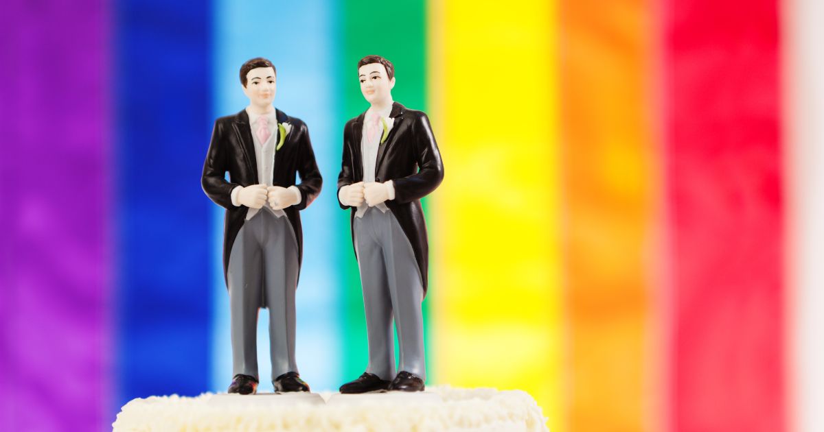 A so-called "gay" marriage wedding cake in front of a pride flag.