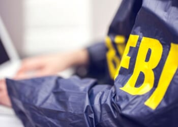 An FBI agent works at a computer in an office.