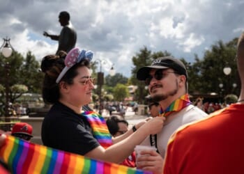 Sydney Saenz of Seattle ties a rainbow handkerchief on Daniel Bonaccorso, also of Seattle, at Disney World's Magic Kingdom on June 3, 2023, in Lake Buena Vista, Florida.