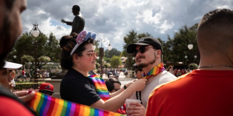 Sydney Saenz of Seattle ties a rainbow handkerchief on Daniel Bonaccorso, also of Seattle, at Disney World's Magic Kingdom on June 3, 2023, in Lake Buena Vista, Florida.