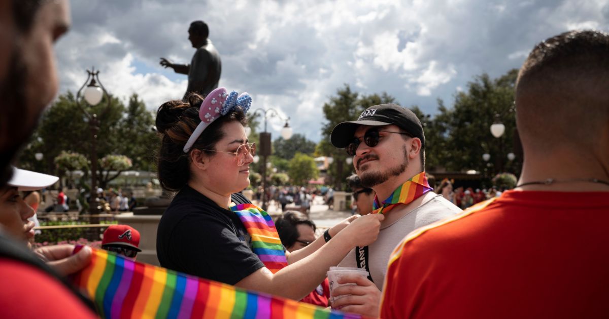 Sydney Saenz of Seattle ties a rainbow handkerchief on Daniel Bonaccorso, also of Seattle, at Disney World's Magic Kingdom on June 3, 2023, in Lake Buena Vista, Florida.
