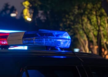 A close-up of a police car light bar flashing red and blue at night.