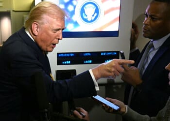President Donald Trump points as he speaks to reporters Friday aboard Air Force One en route to Palm Beach, Florida.
