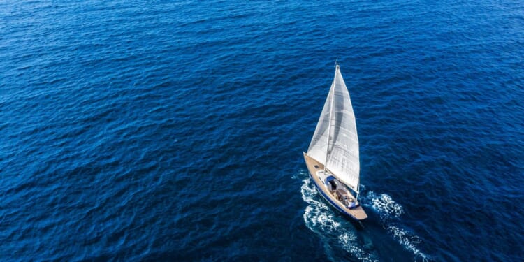An aerial view of a sail boat floating in the Mediterranean sea.