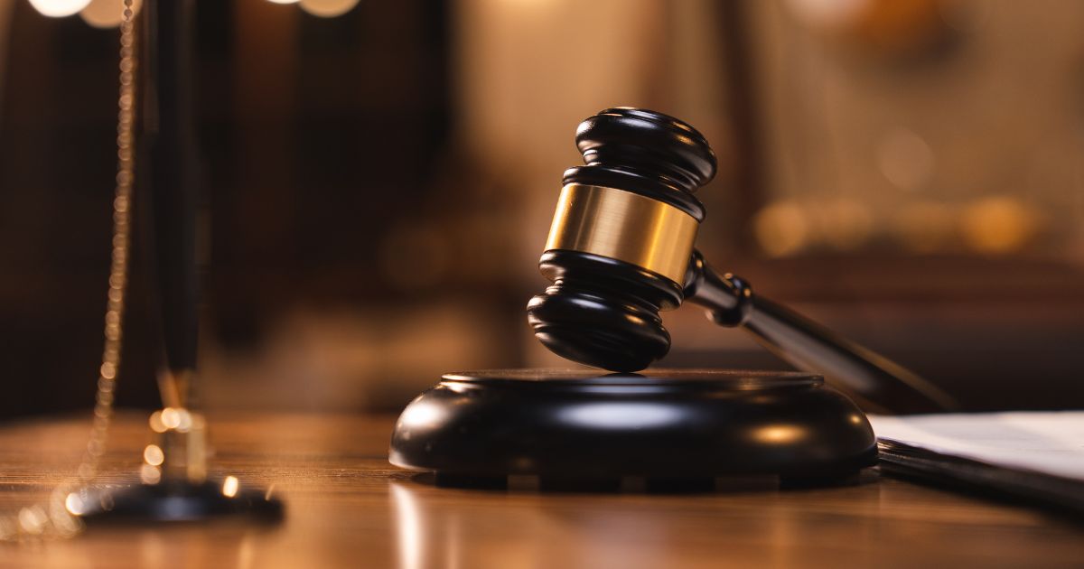 A judges gavel sits on a table as books sit in the background.